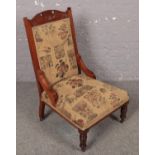 A carved oak upholstered nursing chair with turned supports. Scratches to the legs.