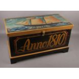 A wooden blanket box with a ship hand-painted on the lid top with the name "Angelica". The front