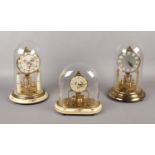 Three Kern Lancel Paris brass torsion clocks, under glass domes