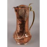 A Newlyn style Arts & Crafts copper jug with brass handle and hinged lid. (Height 32cm). Some