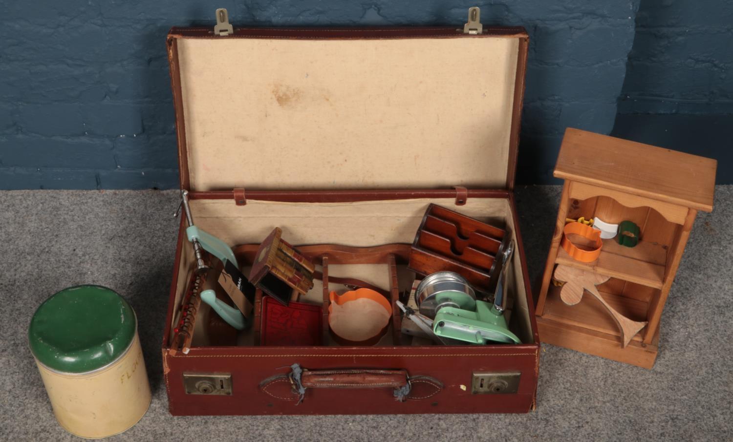 A leather case containing mostly kitchenaila. Including vintage fruit press, flour bin, etc.