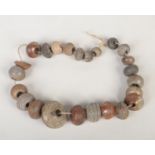 A collection of 18th century saltglazed stoneware spinning weights strung in graduated formation,