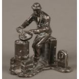 An interesting small silver figure of a seated man cooking on a brazier, Assayed London 1977. Makers