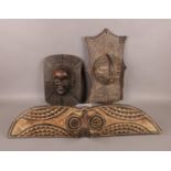 Three African wooden carved wall hangings. Comprising of two tribal masks as examples. Largest