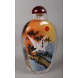 A Chinese glass snuff bottle, reverse painted with a landscape scene and cranes.