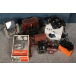A box of camera and projector equipment. Including Kodak brownie box camera, two Nikon coolpix,
