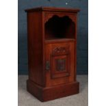 A Mahogany bedside table / cupboard with carved flower detail on front door and metal swing