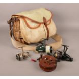 A wicker and canvas fishing creel with contents of four fishing reels. Includes Abu Cardinal 66,