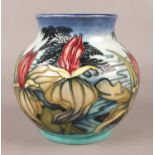 A Moorcroft squat circular vase, decorated in a floral design and boxed. H:14.5cm. Condition good,
