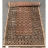 An antique Persian mauve ground Bukhara carpet runner (240cm x 75cm).