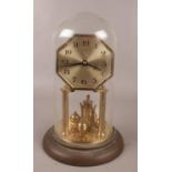 A German brass torsion clock under glass dome. Octagonal dial and Arabic numeral markers.