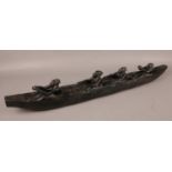 An ebonised carved boat with four African figures inside. All carved from one piece of hardwood.