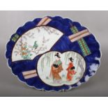 A 19th century Japanese oval dish with panels depicting figures, bird and flowers. Marks to the