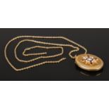 A yellow metal locket on 9ct gold chain. The locket having seed pearl and enamel decoration. Chain