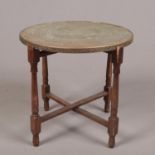 An Indian brass top table on folding wooden base.