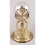 A German brass torsion clock with silvered dial under glass dome.