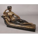 A bronze figure of a reclining semi nude maiden in classical style. (Height 20cm, Length 33cm).