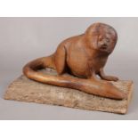 An Oak sculpture of a Golden Lion Tamarin (Monkey) on a slice of tree trunk. H: 23cm, W: 34cm.