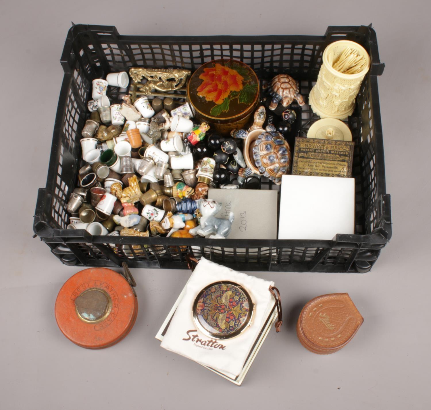 A box of collectables. Includes thimbles, buttons, Stratton compact, Wade etc.