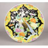 A Japanese polychrome charger decorated on a blackground with a pair of phoenix and peonies,