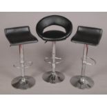 Three bar stools with chrome supports.