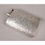 A white metal hipflask with embossed floral decoration.