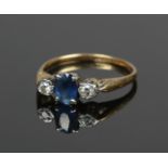 An 18ct gold ring set with a single sapphire, flanked by two diamonds. Size L 1/2, 2.36g.
