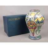 A boxed Moorcroft baluster shaped vase, decorated with hot air balloons.