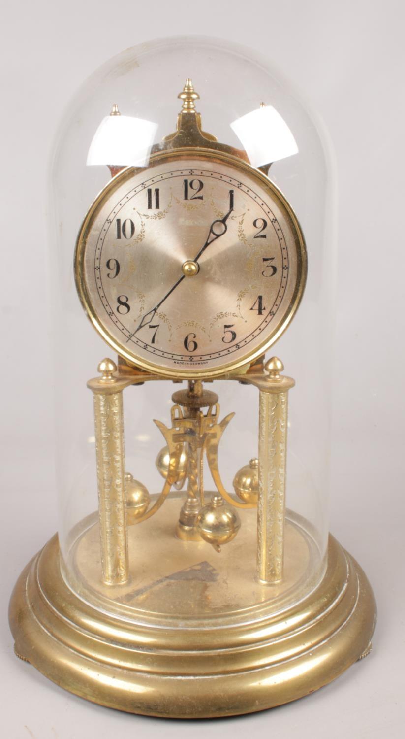 A German brass torsion clock under dome.