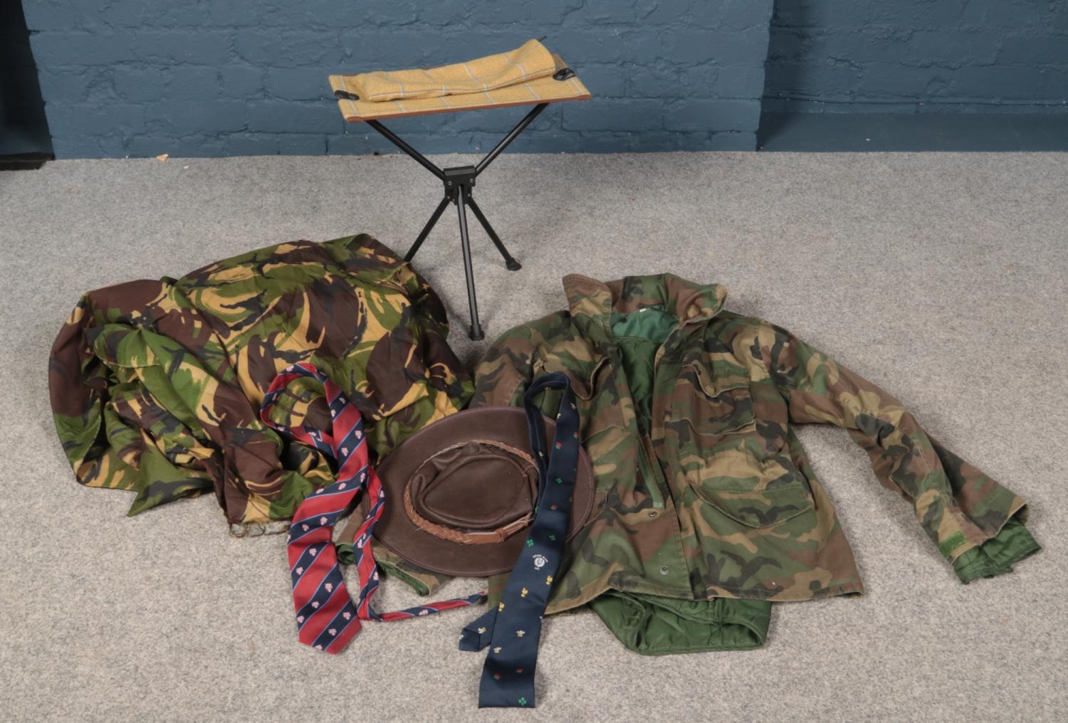 A box of assorted items. Includes camouflage jacket, similar sheet, travel stool, ties and