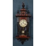 A mahogany cased wall clock. Chiming on a coiled gong. With pendulum and key. Top pediment loose.