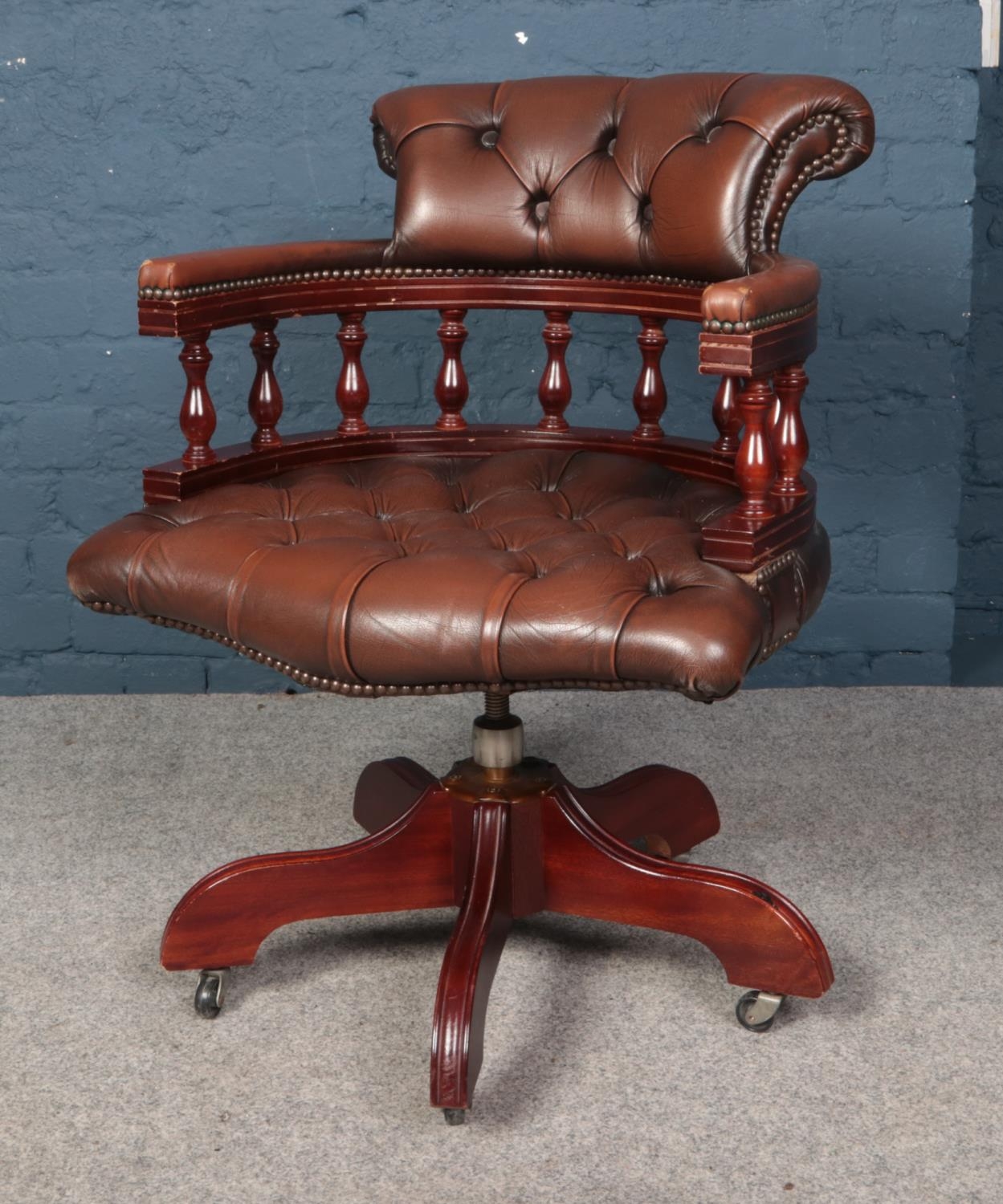 A brown leatherette deep button swivel office chair. Wear to arms.
