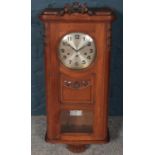 An Edwardian carved mahogany 8 day wall clock. Hour chiming on Westminster. Floral finial loose.