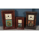 Three American wall clocks with painted glass panels.