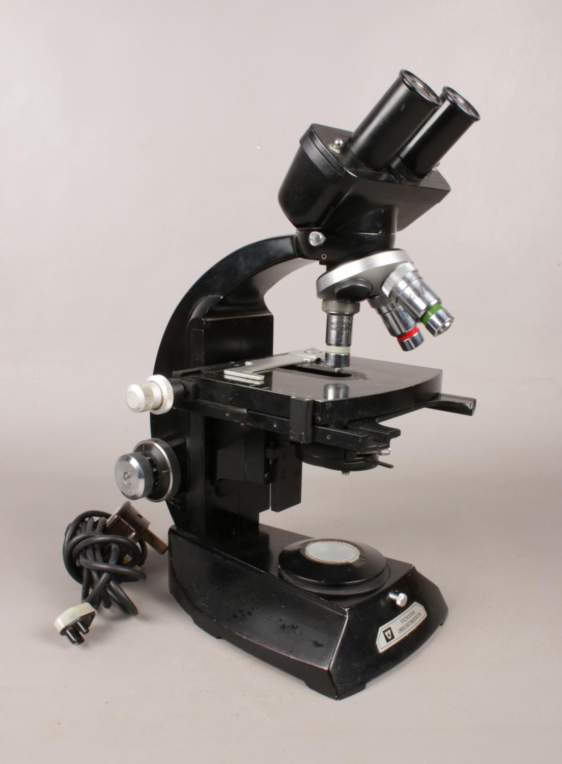 A Vickers instruments electric binocular microscope. H: 35cm, W: 18cm. Vendor confirms this item