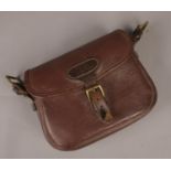 A brown leather cartridge satchel. Monogrammed NS. Includes some contents of gun cleaning equipment.