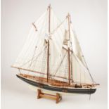 A wooden model of a sail boat on stand.