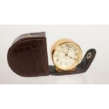 A cased travel "Roger Lascelles" quartz alarm clock in working order. H: 4.5cm, W: 4.5cm.