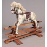 A vintage painted rocking horse supported on a pine wood base.