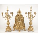 A large ornate brass garniture. Comprising of clock and pair of 5 branch candelabra. (63cm tall) One