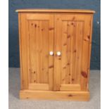 A large Pine two door cupboard with fitted shelving. H: 96cm, W:77cm, D: 45.5cm. Condition good.