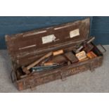 A metal tool case of vintage hand tools. Including hammers, saws, hand crack screwdrivers, wood