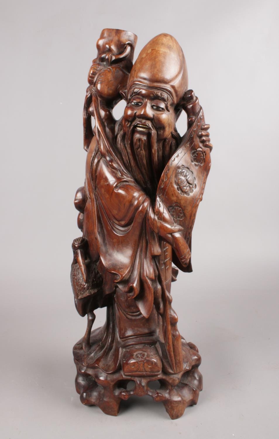 A hardwood oriental carved figure depicting a sage figure with scroll. This figure has ivory