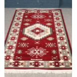 An Aztec style wool & silk rug in red, cream and pale green. H:205cm, W: 128.5cm. Condition good.