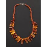 A cased cognac amber necklace comprising approximately 150 shaped and graduated beads with safe lock