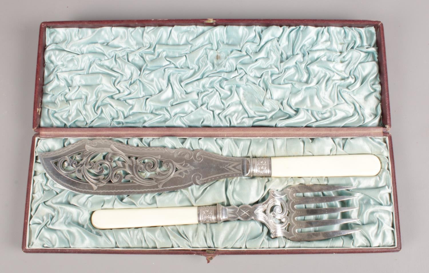 A cased silver plate fish knife and fork with bone handle and pierced decoration.