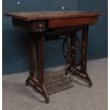 A 'Singer' sewing machine table with named foot peddle. H: 74cm, W:79cm,D:42cm. Condition age worn.