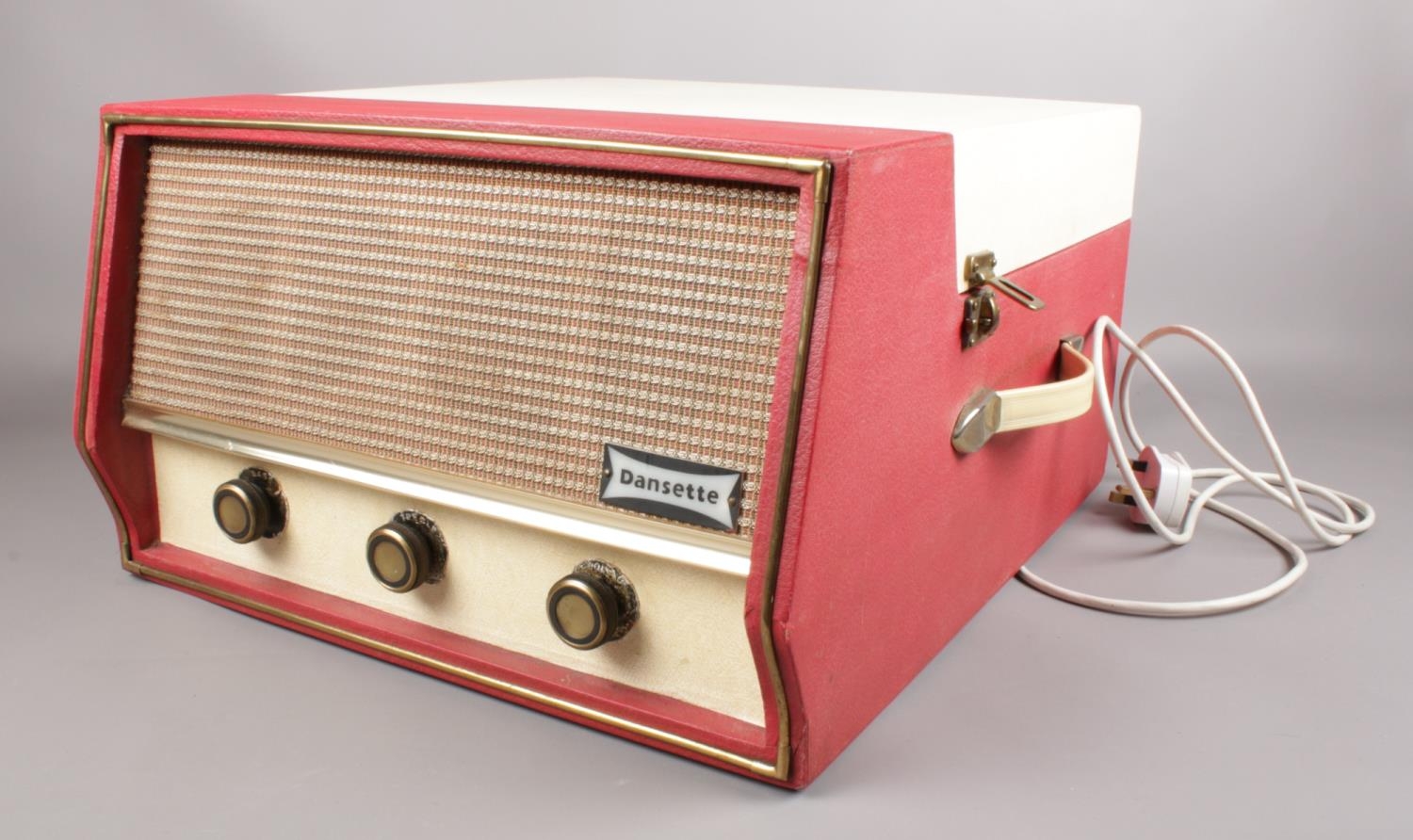 A Dansette 'Conquest Auto' portable record player (missing legs) in red and cream. H:25.5cm, W: 40.