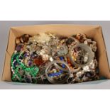 A box of costume jewellery. Includes shell necklace, white metal bangle, beads etc.