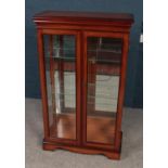 A mahogany glazed display cabinet. With mirrored back. (125.5cm x 75cm x 32cm).